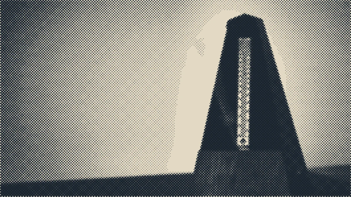 A metronome standing on a piano.